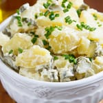 Kulhollinen perunasalaattia, jonka päällä ruohosipulia.