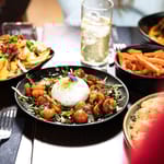 Ravintolapöydässä annoksia ja juomnia. Etualalla mozzarellaa ja tomaatteja.