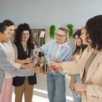 7 naista juomassa kuohuviiniä toimistolla.