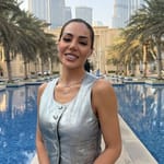 Sofia Belórf hopeisessa liivissä Dubaissa, taustalla palmuja, allas ja Burj Khalifa -pilvenpiirtäjä.