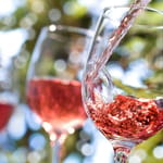 Roséviiniä kaadetaan lasiin ulkona kesäpäivänä — suomalaisten kesäjuominen muuttui, rosé on noussut lonkeron rinnalle