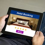 Henkilö pitää tablettia sylissään ja selaa hotellivarausta — viisi tähteä näytöllä ei kerro hotellin todellisesta laadusta kaikkea
