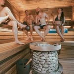 Ihmisiä saunomassa ja nauttimassa olutta kiukaan vierellä