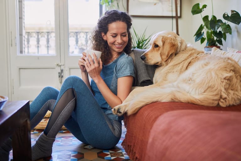 Nainen nojaa sohvaan kultainen noutaja vierellään