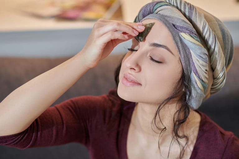 Henkilö painaa kiveä silmät suljettuina otsaansa ja hänellä on turbaani.