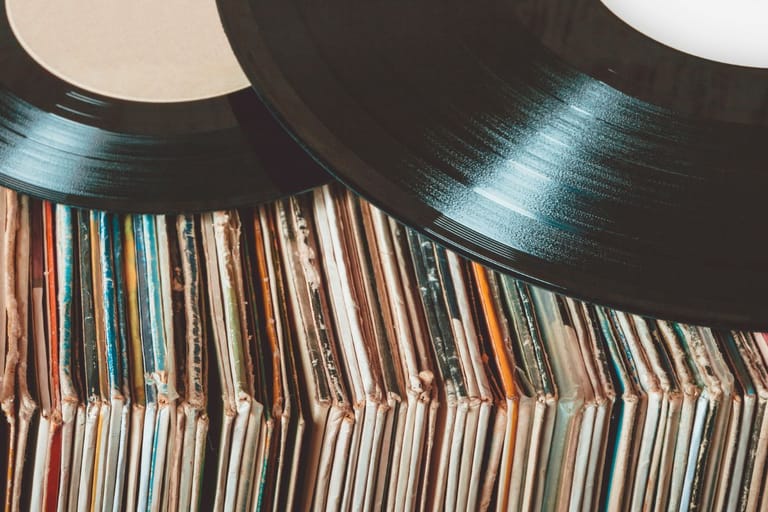 Kaksi vinyylilevyä levyhyllyrivin päällä.