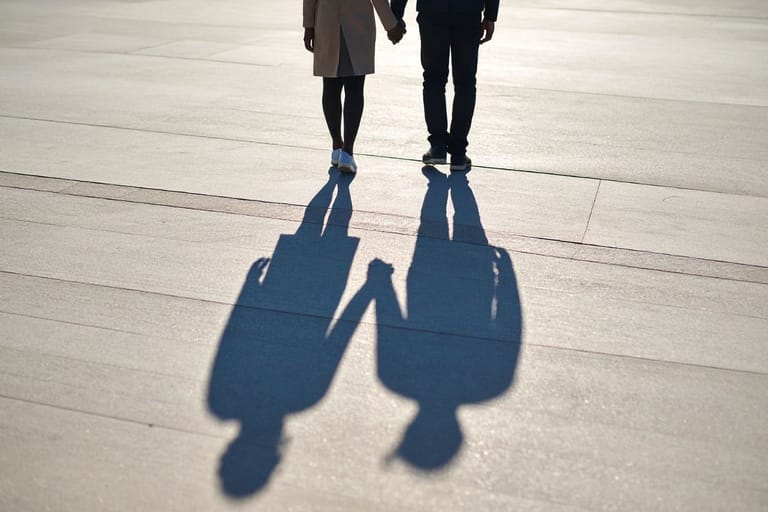 Kahden ihmisen varjot näkyvät heidän kävellessään käsi kädessä.