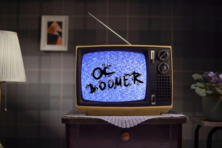 Vanha putkitelevisio huonekalun päällä, ruudulla teksti ”OK Boomer”, ympärillä retrohenkinen sisustus.