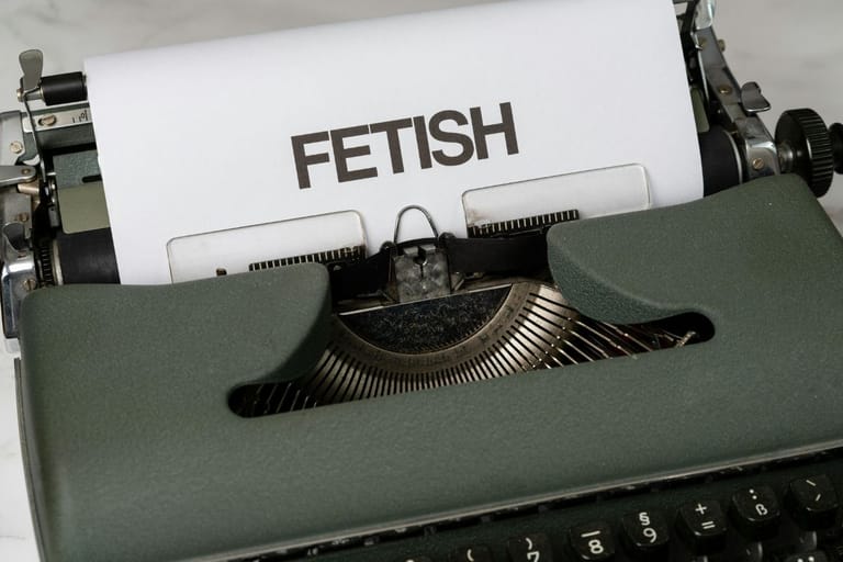 Vanhanaikainen kirjoituskone, jossa on A4:n paperi. Paperiin on kirjoitettu "FETISH" isoilla kirjaimilla.