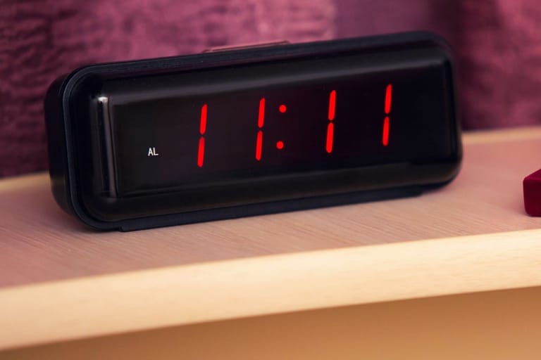 Digitaalinen herätyskello pöydällä, näytössä kellonaika 11:11