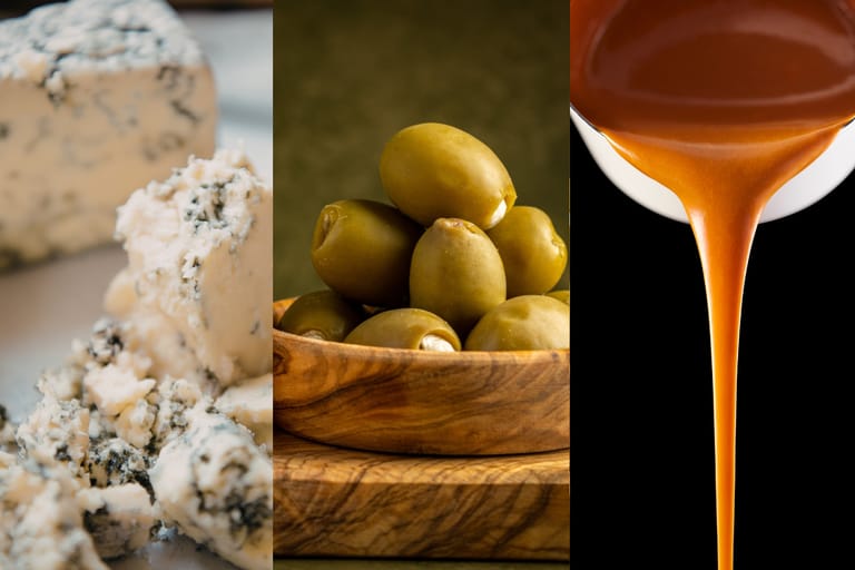 Kolmiosainen lähikuva ruoasta: vasemmalla murenevaa sinihomejuustoa, keskellä vihreitä oliiveja puisessa kulhossa ja oikealla siipikastiketta, joka valuu lusikasta hitaana nauhana.