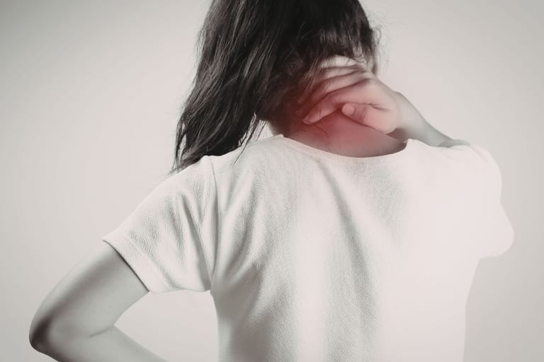 Nainen hieroo niskaansa ja hartiaansa, niska-hartiaseutu punoittaa kivun merkiksi.