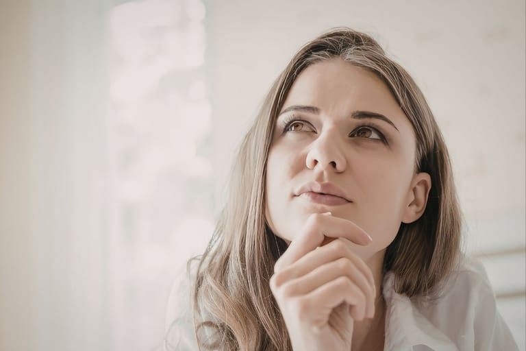 Nuori nainen katsoo ylös mietteliäänä ja pohtii ajatuksiaan valoisassa sisätilassa