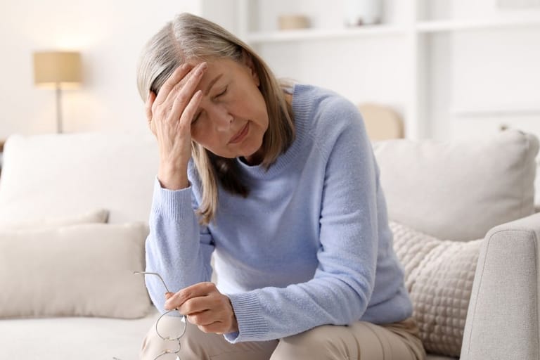Väsynyt nainen pitelee päätään sohvalla – jatkuva uupumus voi liittyä matalaan ferritiiniin