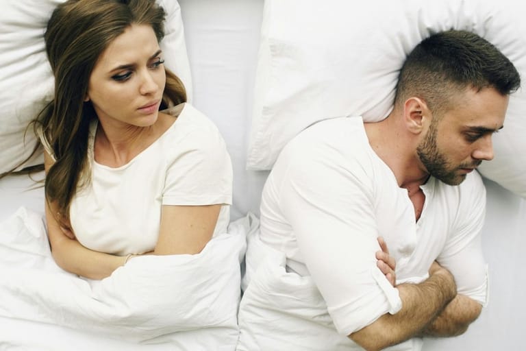 Pariskunta riidan jälkeen sängyssä selin toisiinsa – etäinen tunnelma