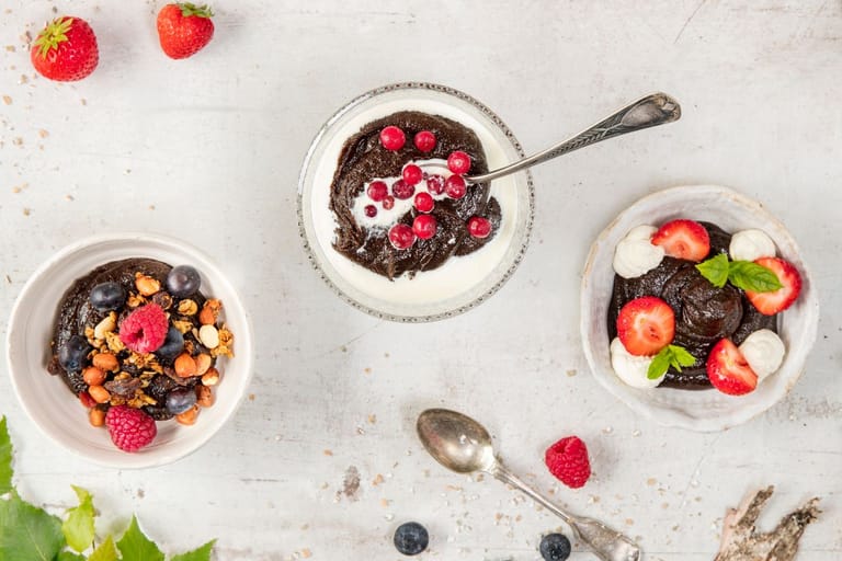 Mämmistä valmistettuja jälkiruokia kulhossa pöydällä. Vieressä marjoja.