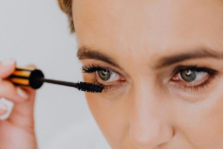 Nainen levittää ripsiväriä ripsiinsä lähikuvassa.