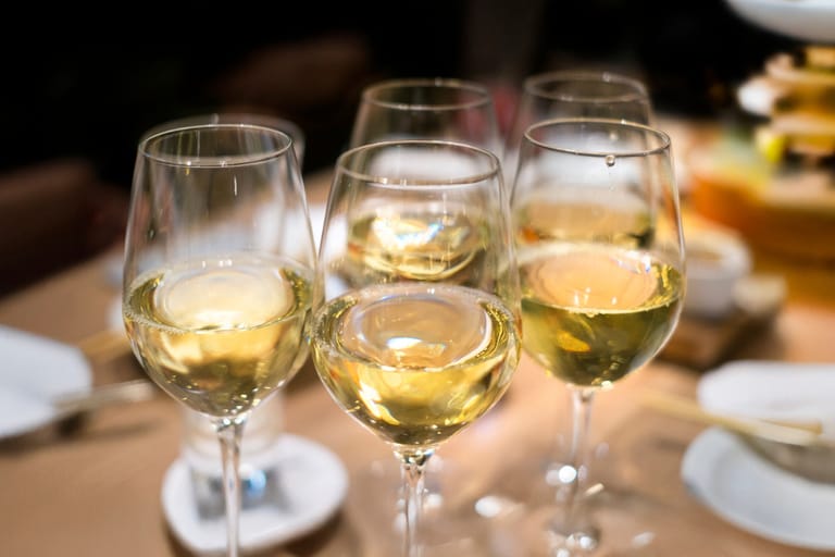 Valkoviinilaseja rivissä pöydällä.