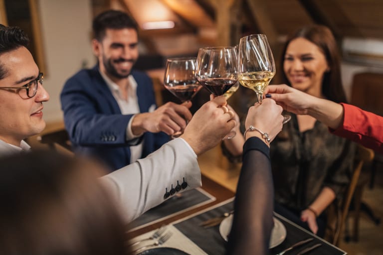 Useita ihmisiä juomassa viiniä ja kippistelemässä laseja yhteen.
