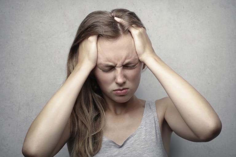 ahdistunut nuori nainen pitelee päätään stressin ja ahdistuksen keskellä