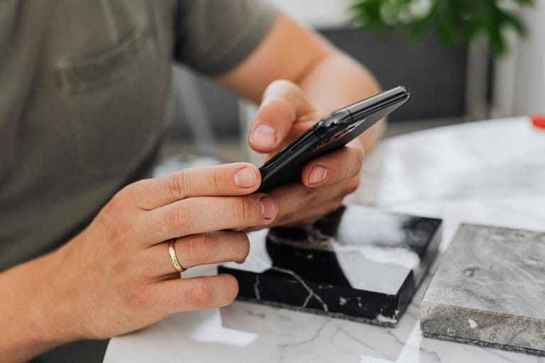 Kädet selaavat älypuhelinta – jatkuva skrollaaminen voi kuormittaa kehoa huomaamatta