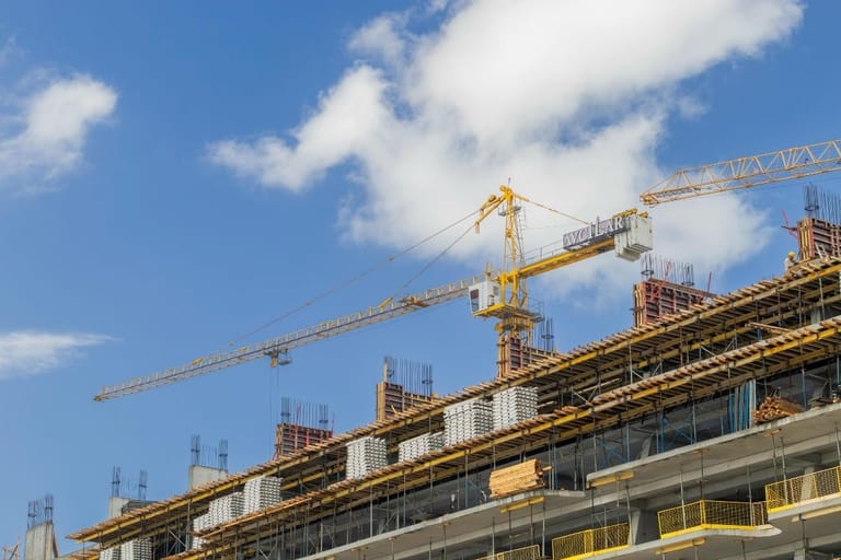Rakennustyömaa Suomessa hidastuneen rakentamisen aikana – nosturit ja keskeneräinen kerrostalo