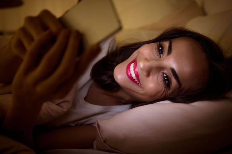 myöhään valvova nainen puhelin sängyssä yökyöpeli unirytmi iltaihminen