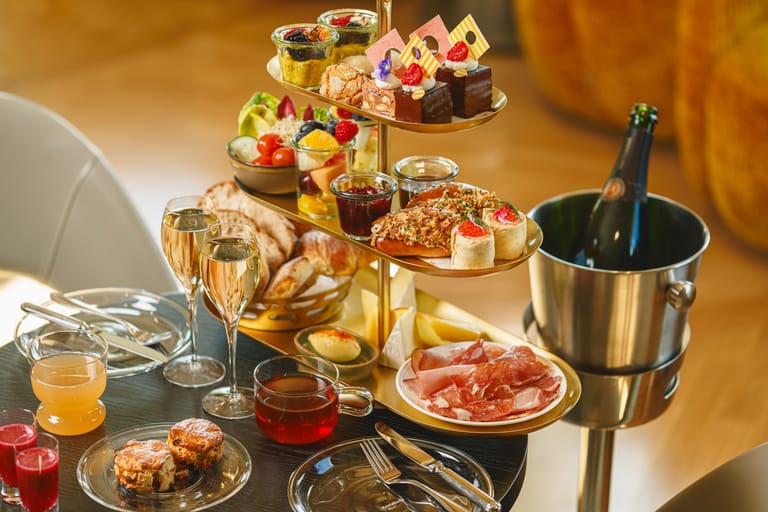 Runsas brunssitarjoilu kerrostarjottimella, kuohuviiniä ja erilaisia herkkuja pöydällä.