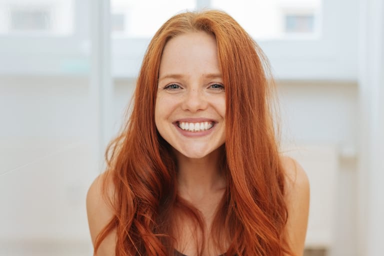 Punatukkainen nainen hymyilee kameralle.