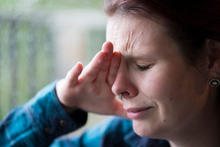 Nainen itkee ja pitelee toiselle kädellä päätään.