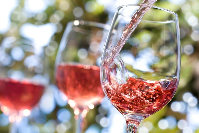 Roséviiniä kaadetaan lasiin ulkona kesäpäivänä — suomalaisten kesäjuominen muuttui, rosé on noussut lonkeron rinnalle