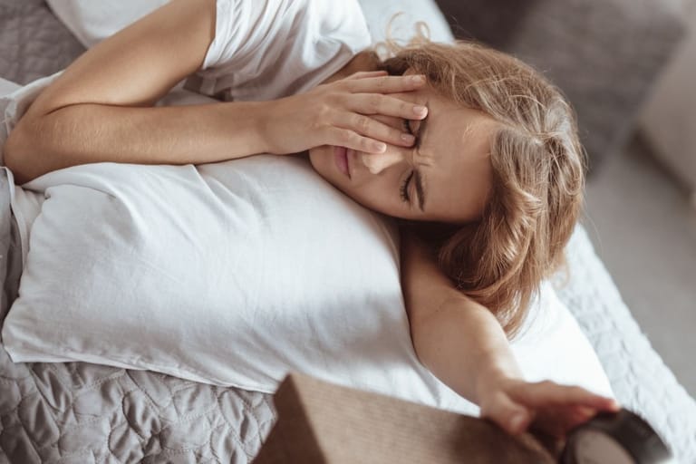 Nainen makaa sängyssä aamulla käsi silmiensä päällä heräten — tutkijat selvittivät miksi jotkut ihmiset muistavat unensa tarkasti ja mitä se paljastaa persoonallisuudesta