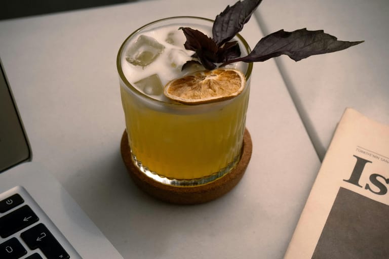 Cocktaili pöydällä. Vieressä kannettava tietokone ja sanomalehti.