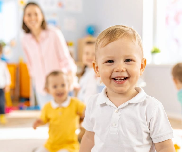 Lapsia valoisassa varhaiskasvatustilassa. Etualalla pikkuinen leikki-ikäinen.