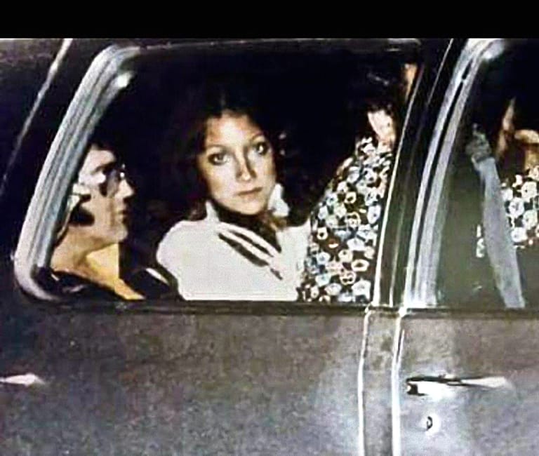 Paparazzikuva Mindi Milleristä ja Elviksestä autossa. Mindi katsoo suoraan kameraan, kun Elviksestä näkyy silmälasit ja leuka.