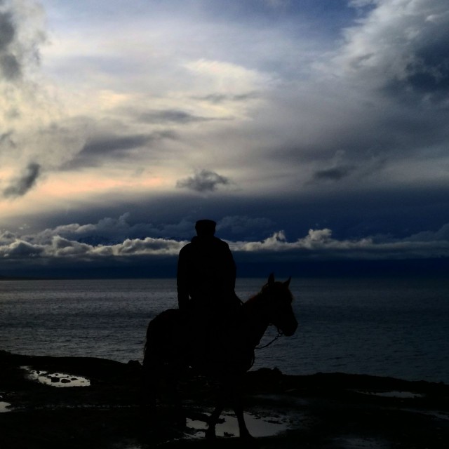 Kiinassa moottoripyörällä. Kohtaaminen Kazakki ratsastajan kanssa. Xingjiang, lake.
