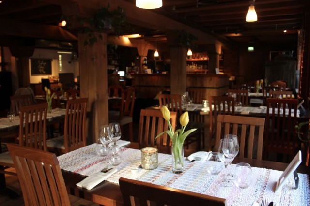 Ruokailutilojen hirsipalkit muistuttavat rakennuksen historiasta. Pöytien kaitaliinat on kudottu Finlaysonin ylijäämätekstiileistä, ja ne luovat ravintolaan rentoa hygge-tunnelmaa.