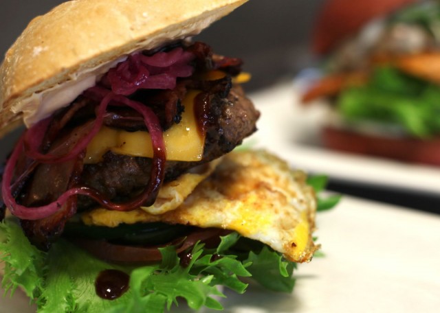 Uudistuneesta house burgerissa on BBQ-kastiketta, cheddarjuustoa, paistettu luomumuna, marinoitua pekonia, sipulia ja mummonkurkkua.