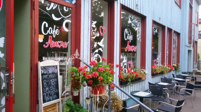 Cafe Amore on perustettu vanhaan siniseen puutaloon, jonka isoja ikkunoita koristaa värikäs kasvillisuus.