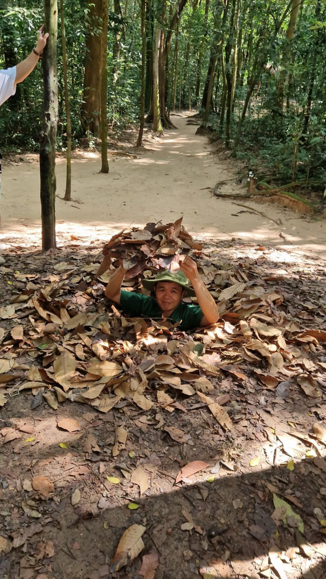 Vietnamilainen opas näyttää Cu Chissa miten tunneliin mennään.