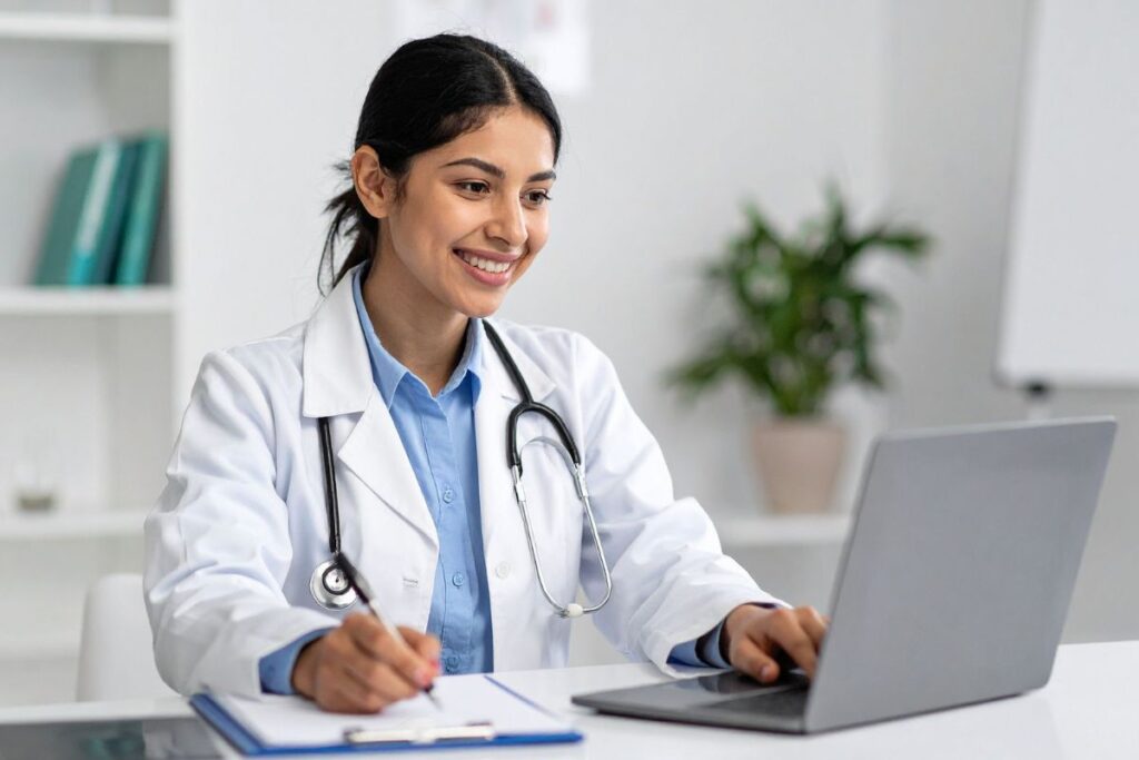 Naislääkäri työtakki päällään katselee tietokonetta