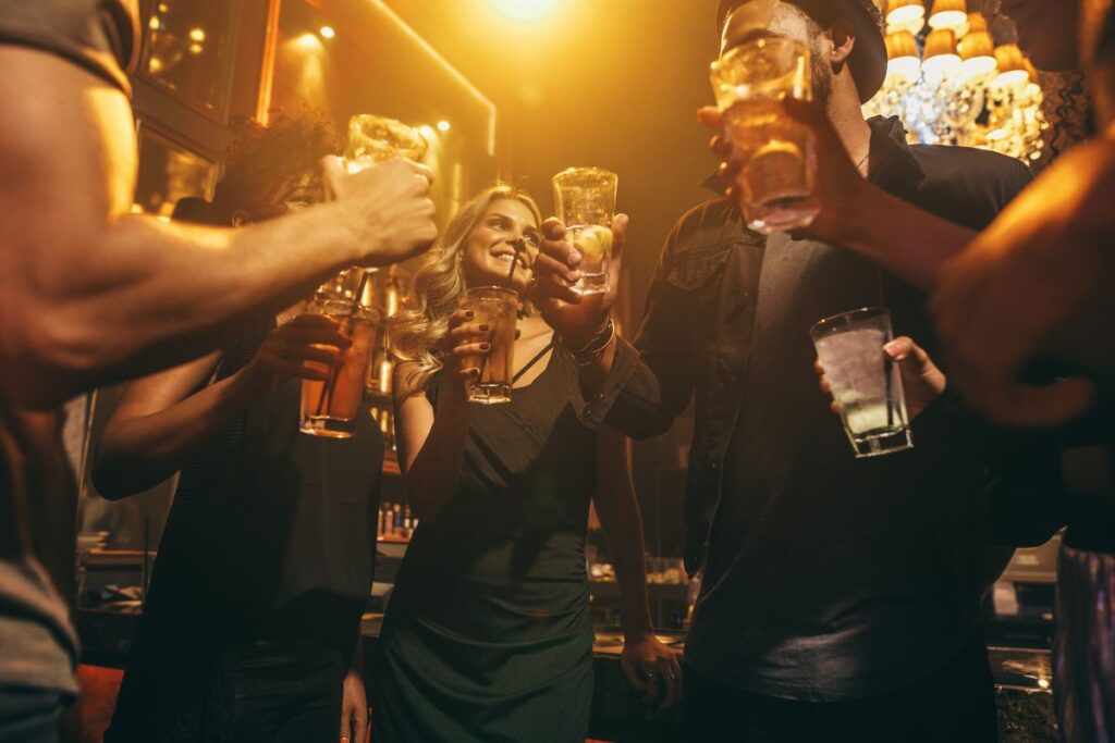 Kuvituskuva, jossa nuoret aikuiset hengailevat porukassa baarissa. Kuvassa on baarivalaistus ja letkeä tunnelma. 