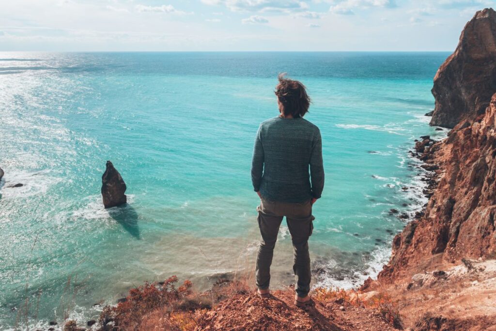 mies rantakallioilla katsomassa aavaa merta