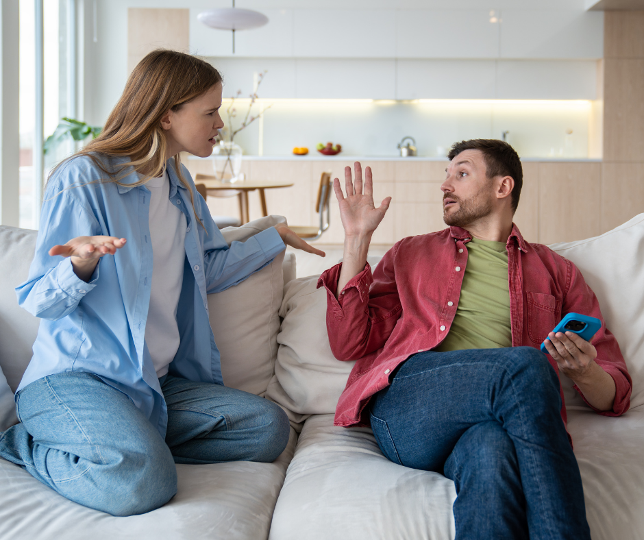 Kuvassa mies ja nainen riitelevät sohvalla. Nainen levittelee käsiään ja mies on nostanut käden pystyyn.