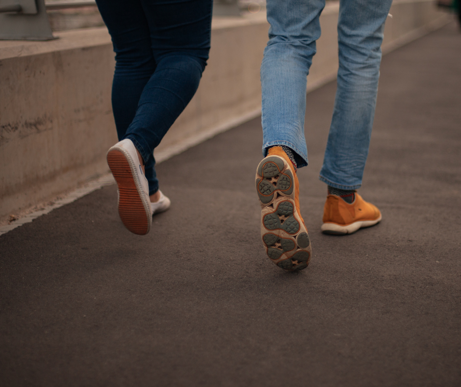 Kuvassa näkyy kahden ihmisen jalat kävelemässä kadulla.