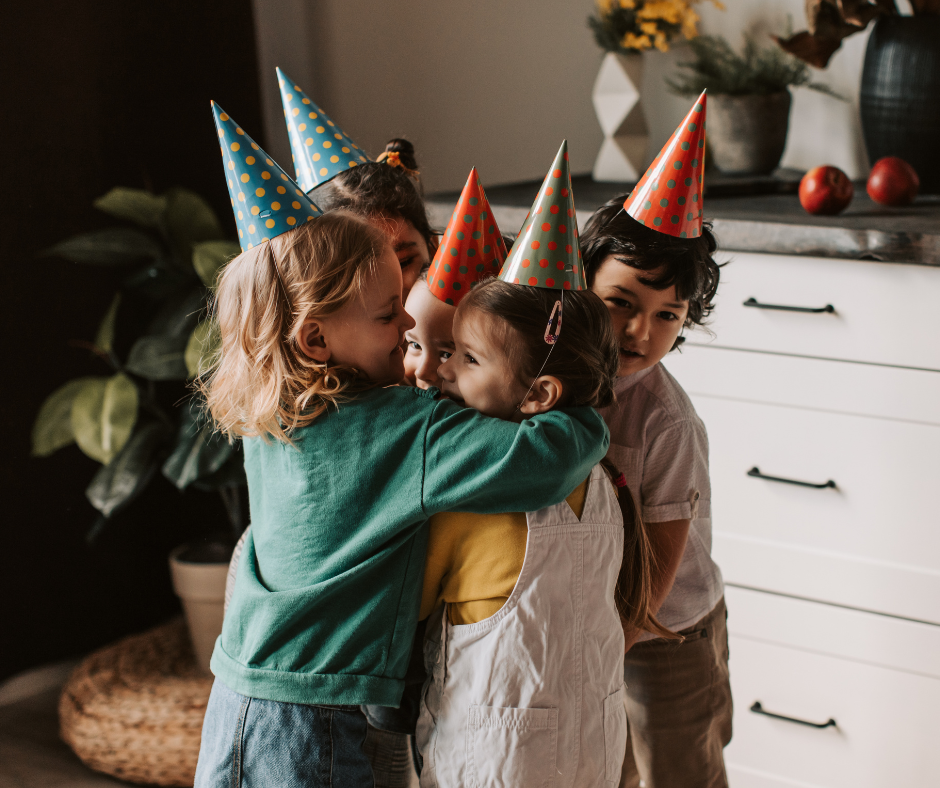 Kuvassa viisi sisarusta halaa lastenkutsuilla toisiaan juhlahatut päissään.