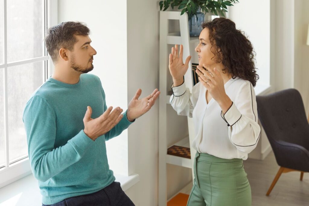 Molemmat puhuvat kiivaasti ja elehtivät käsillään. pari on olohuoneenomaisessa ympäristössä.