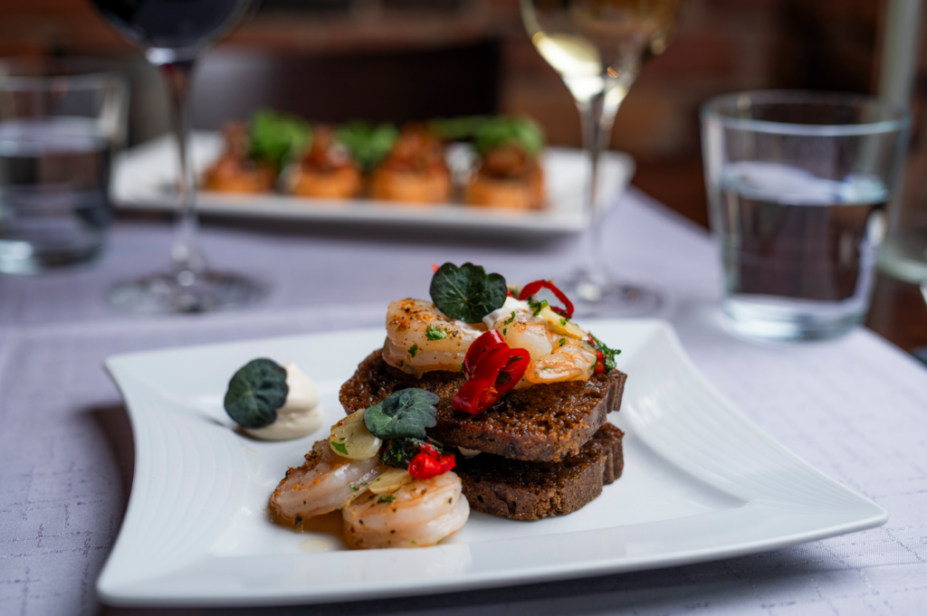 Katkarapuja ja tummaa leipää pieninä annospaloina valkoisella lautasella.