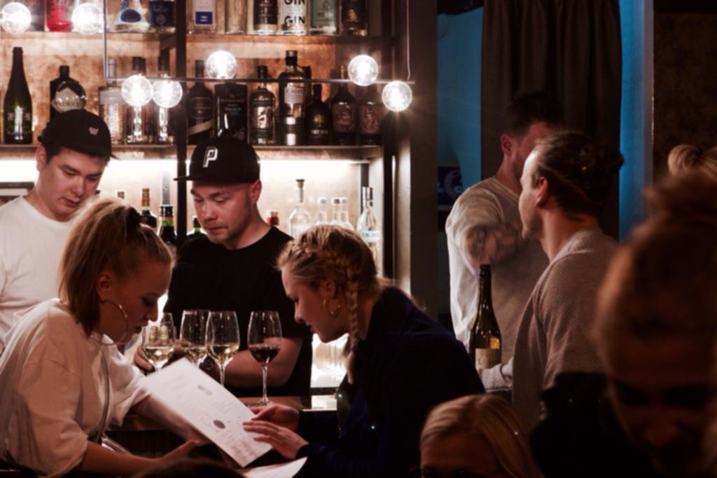 The Bull & The Firm ravintolassa asiakkaita baaritiskillä, henkilökunta esittelee juomalistaa.