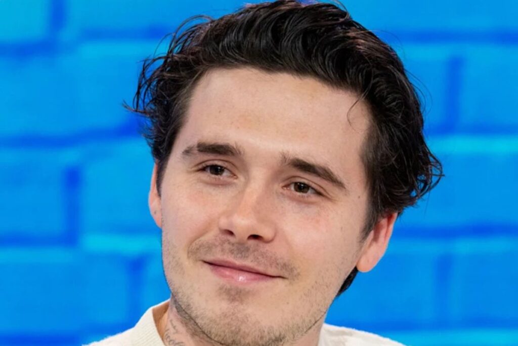 Tummahiuksinen nuorukaisen kasvot sinistä tiiliseinää vasten.